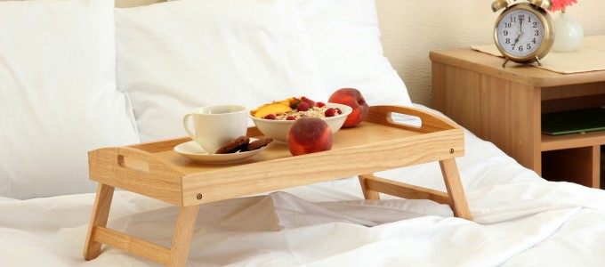 wooden tray with light breakfast on bed